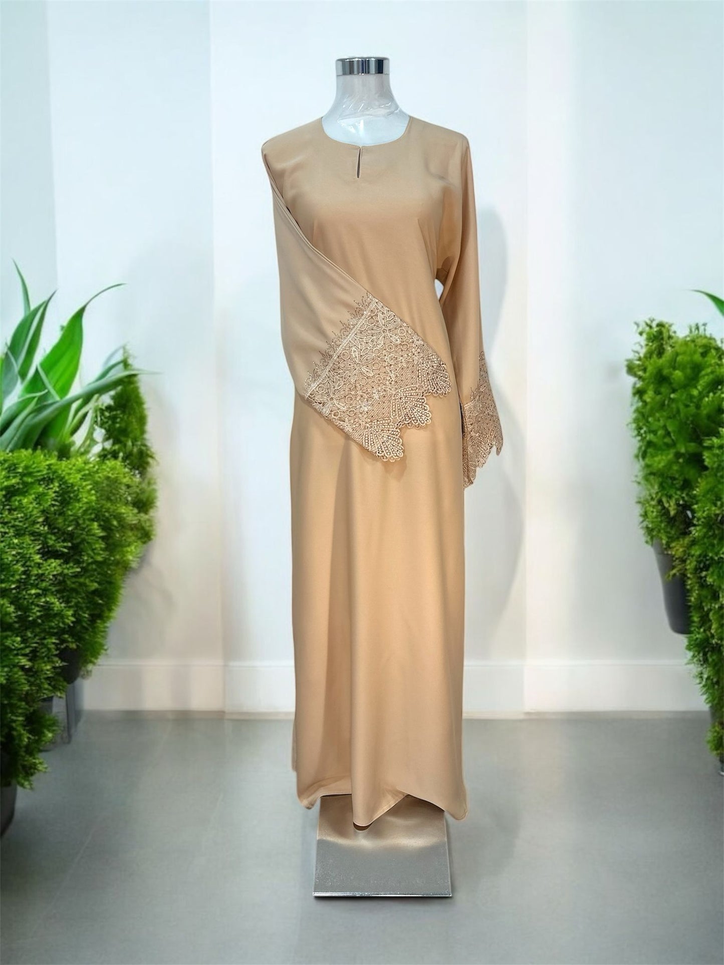 Beige Nisa jubah falls in a clean, elongated line, creating a flattering drape that moves beautifully with every step. A subtle V-notched round neckline adds a modern touch, while the standout feature lies in the delicately crafted lace cuffs—intricately detailed to elevate the overall design with a hint of femininity and refinement and it is paired with a shawl.