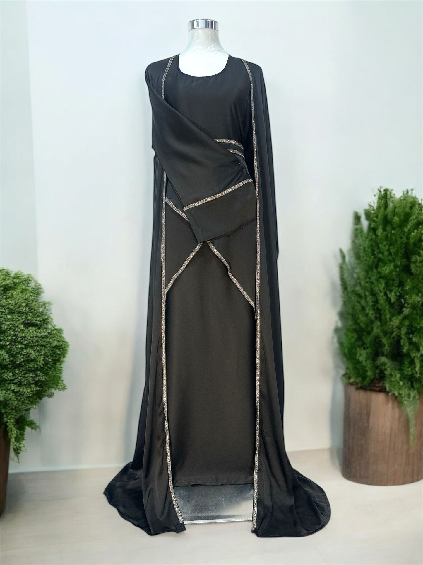 Amara Abaya features a flowing silhouette with a graceful, floor-length design that exudes sophistication. Delicate embellishments outline the edges of the abaya, adding a subtle shimmer and refined contrast to the fabric. The garment includes a matching inner dress, creating a layered effect that enhances its modest yet stylish appeal.
