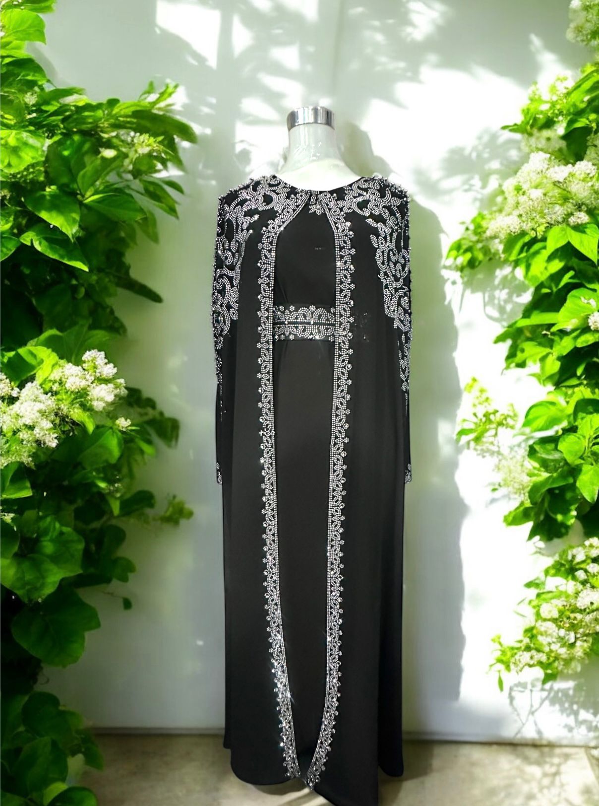 A black abaya designed with a flowing cape, delicately adorned with shimmering stone embellishments for a graceful and sophisticated finish.


