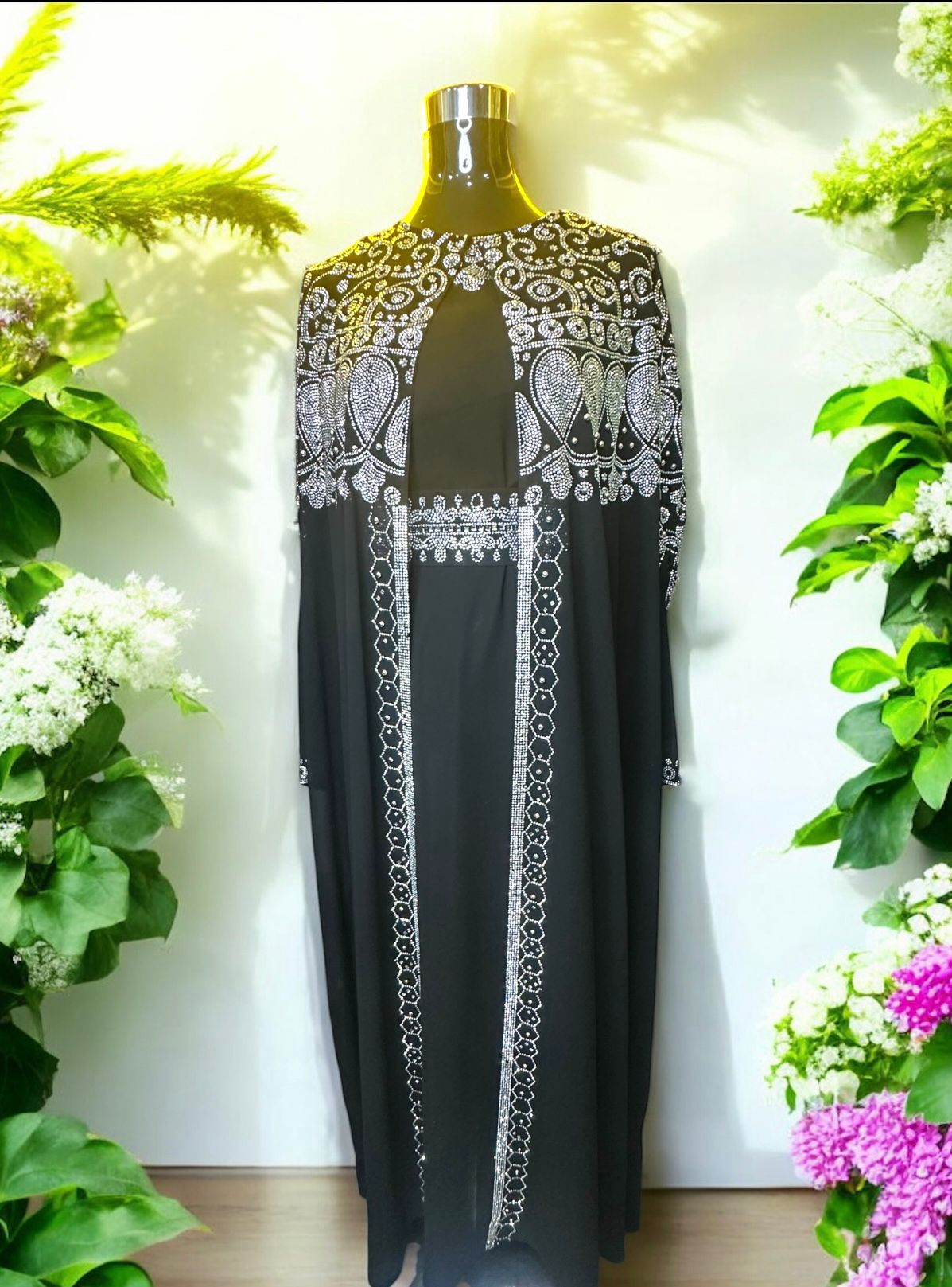 A black abaya designed with a flowing cape, delicately adorned with shimmering stone embellishments for a graceful and sophisticated finish.


