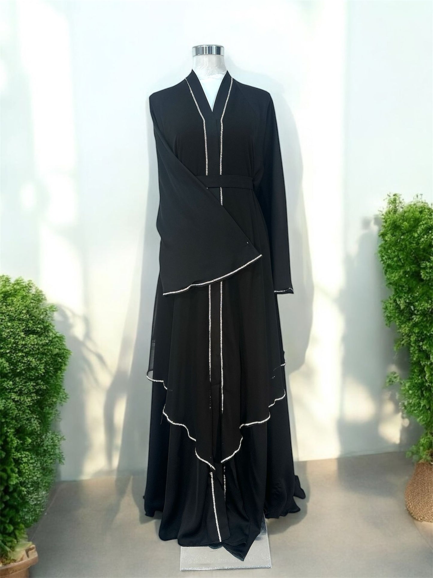 Malika Abaya was designed with flowing layered panels that create beautiful movement and a sophisticated silhouette. The delicate contrast trim detailing along the neckline, front panels, sleeves, and cascading layers adds a refined and modern touch.

Featuring wide flare sleeves and a matching waist belt, this piece offers both comfort and a flattering fit.