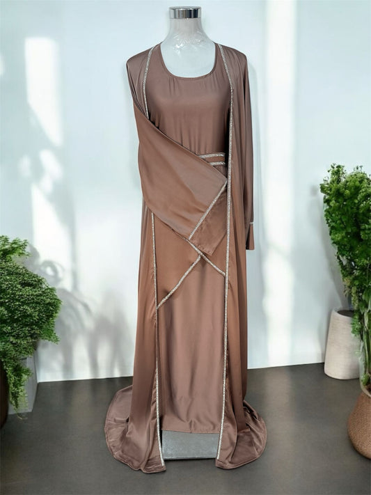 Amara Abaya features a flowing silhouette with a graceful, floor-length design that exudes sophistication. Delicate embellishments outline the edges of the abaya, adding a subtle shimmer and refined contrast to the fabric. The garment includes a matching inner dress, creating a layered effect that enhances its modest yet stylish appeal.