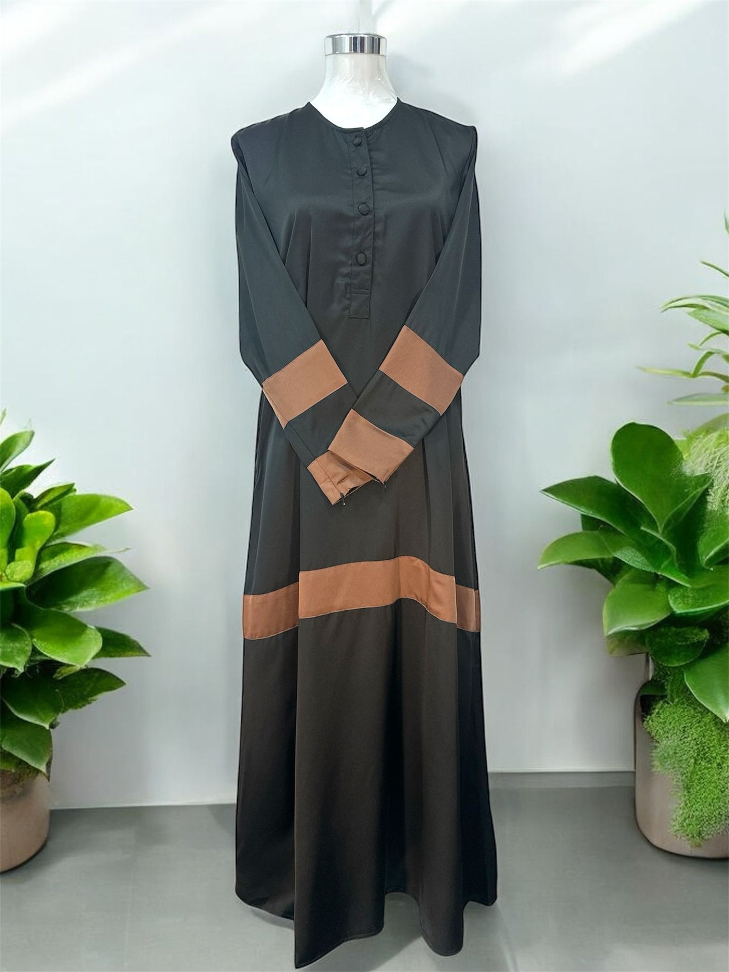 Brown Liniah jubah is tailored in loose, flowy silhouette that drapes beautifully, offering both comfort and sophistication. A round neckline with a buttoned front placket adds subtle structure, while the wide contrast cuffs and matching hem panel create a striking, coordinated look.