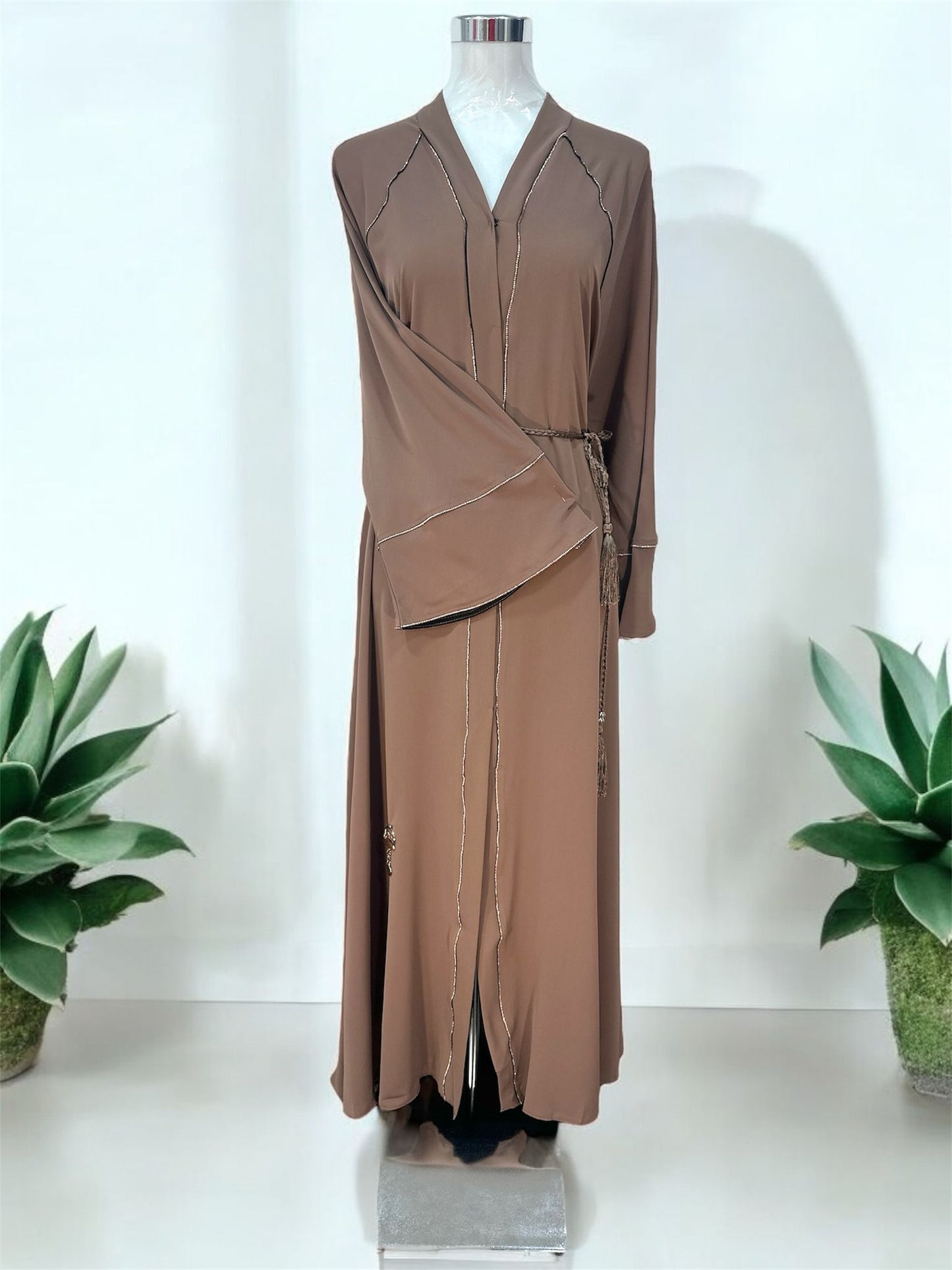 Turab Abaya features delicate contrast piping details along the neckline, front panels, and sleeves for a refined and polished finish.

The wide flare sleeves add graceful movement, while the matching rope-style waist tie with tassel accents enhances the overall feminine look.