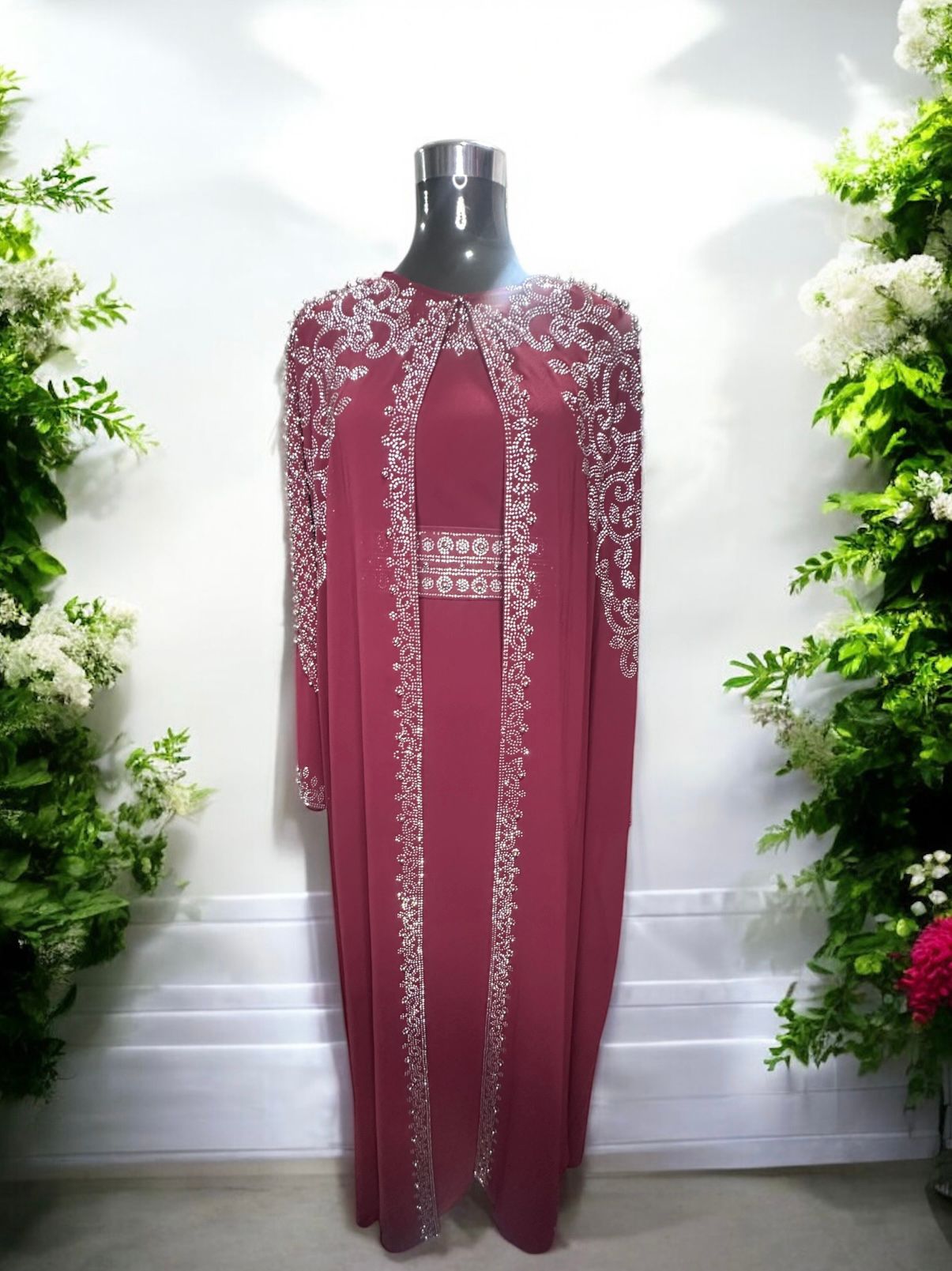 A Burgundy abaya designed with a flowing cape, delicately adorned with shimmering stone embellishments for a graceful and sophisticated finish.