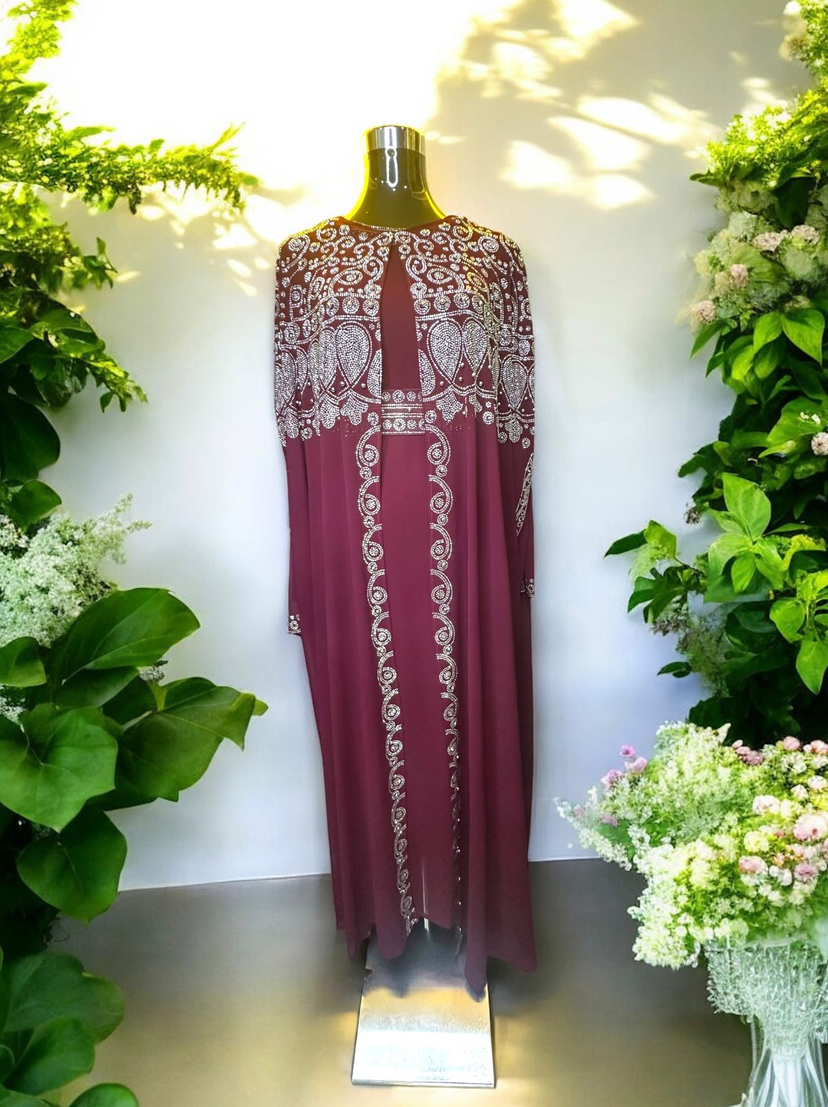 A Burgundy abaya designed with a flowing cape, delicately adorned with shimmering stone embellishments for a graceful and sophisticated finish.


