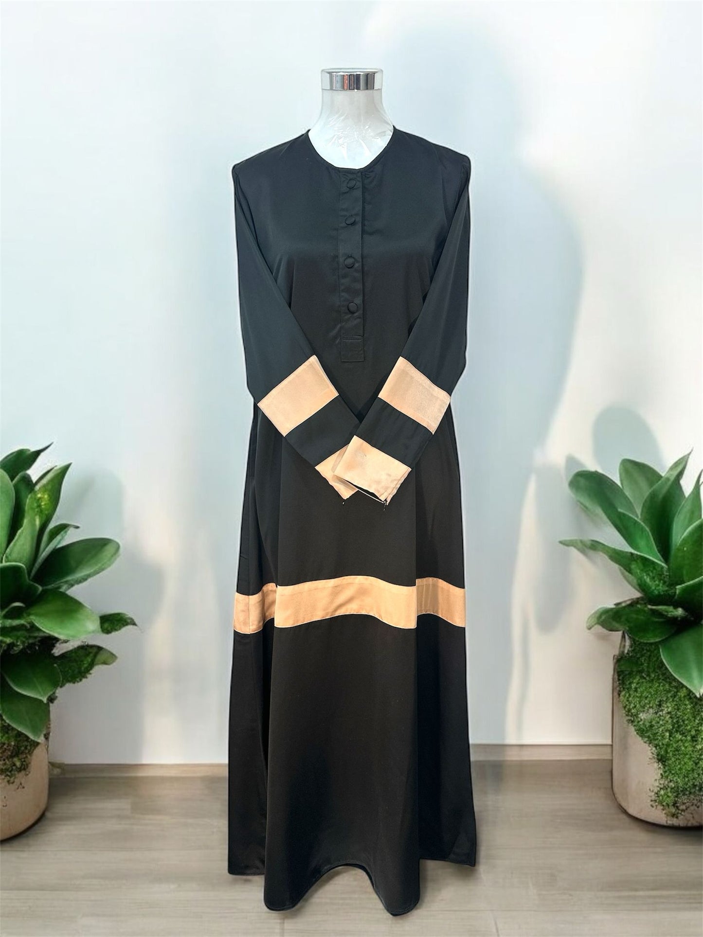 Champagne Liniah jubah is tailored in loose, flowy silhouette that drapes beautifully, offering both comfort and sophistication. A round neckline with a buttoned front placket adds subtle structure, while the wide contrast cuffs and matching hem panel create a striking, coordinated look.