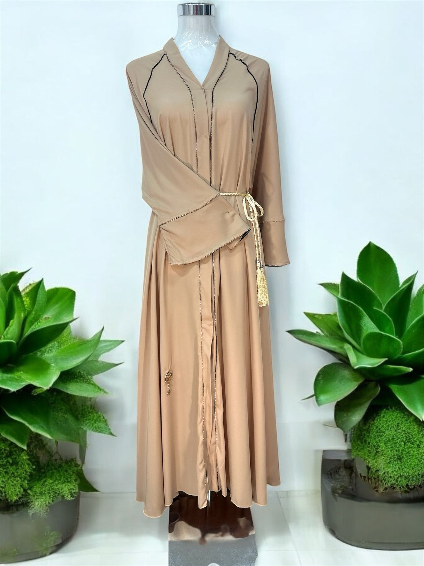 Turab Abaya features delicate contrast piping details along the neckline, front panels, and sleeves for a refined and polished finish.

The wide flare sleeves add graceful movement, while the matching rope-style waist tie with tassel accents enhances the overall feminine look.