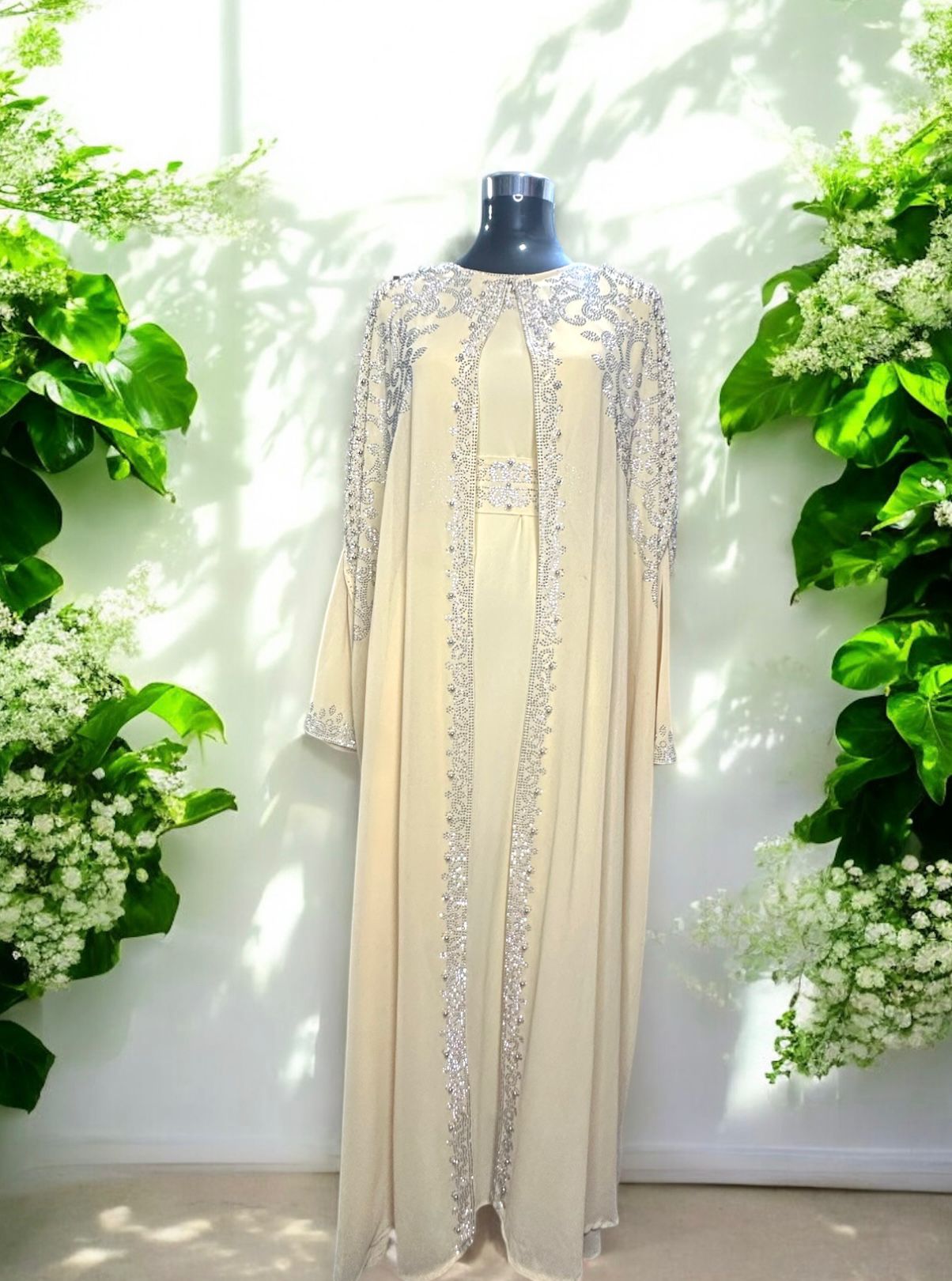 A creme abaya designed with a flowing cape, delicately adorned with shimmering stone embellishments for a graceful and sophisticated finish.


