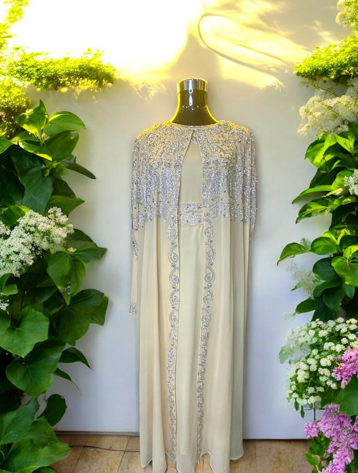 A creme abaya designed with a flowing cape, delicately adorned with shimmering stone embellishments for a graceful and sophisticated finish.



