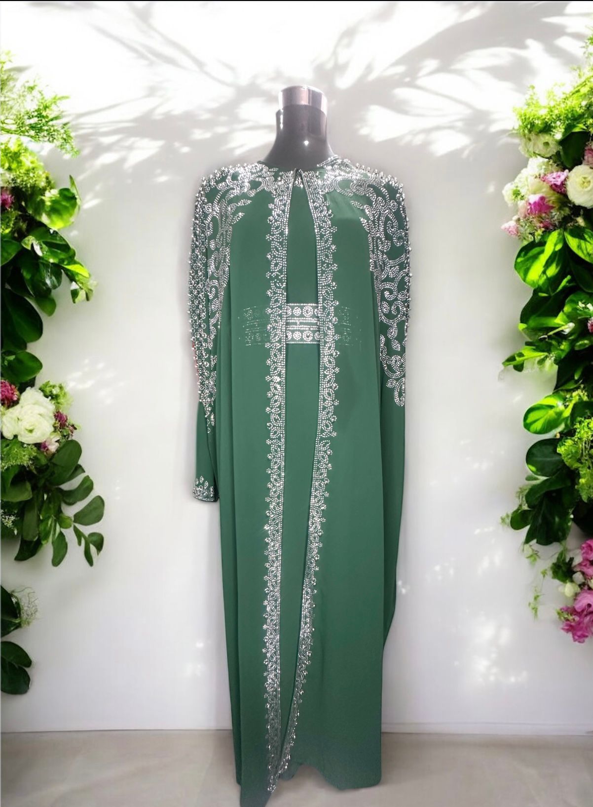 A green abaya designed with a flowing cape, delicately adorned with shimmering stone embellishments for a graceful and sophisticated finish.


