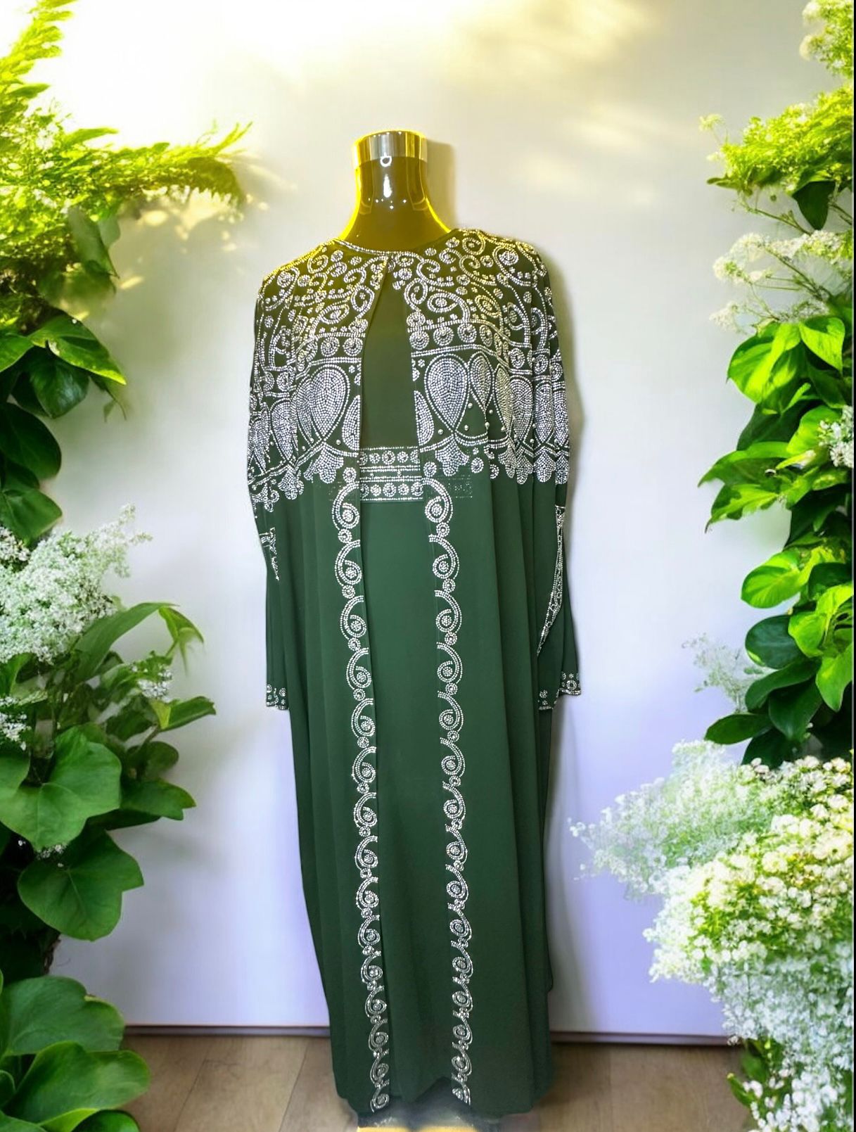 A green abaya designed with a flowing cape, delicately adorned with shimmering stone embellishments for a graceful and sophisticated finish.


