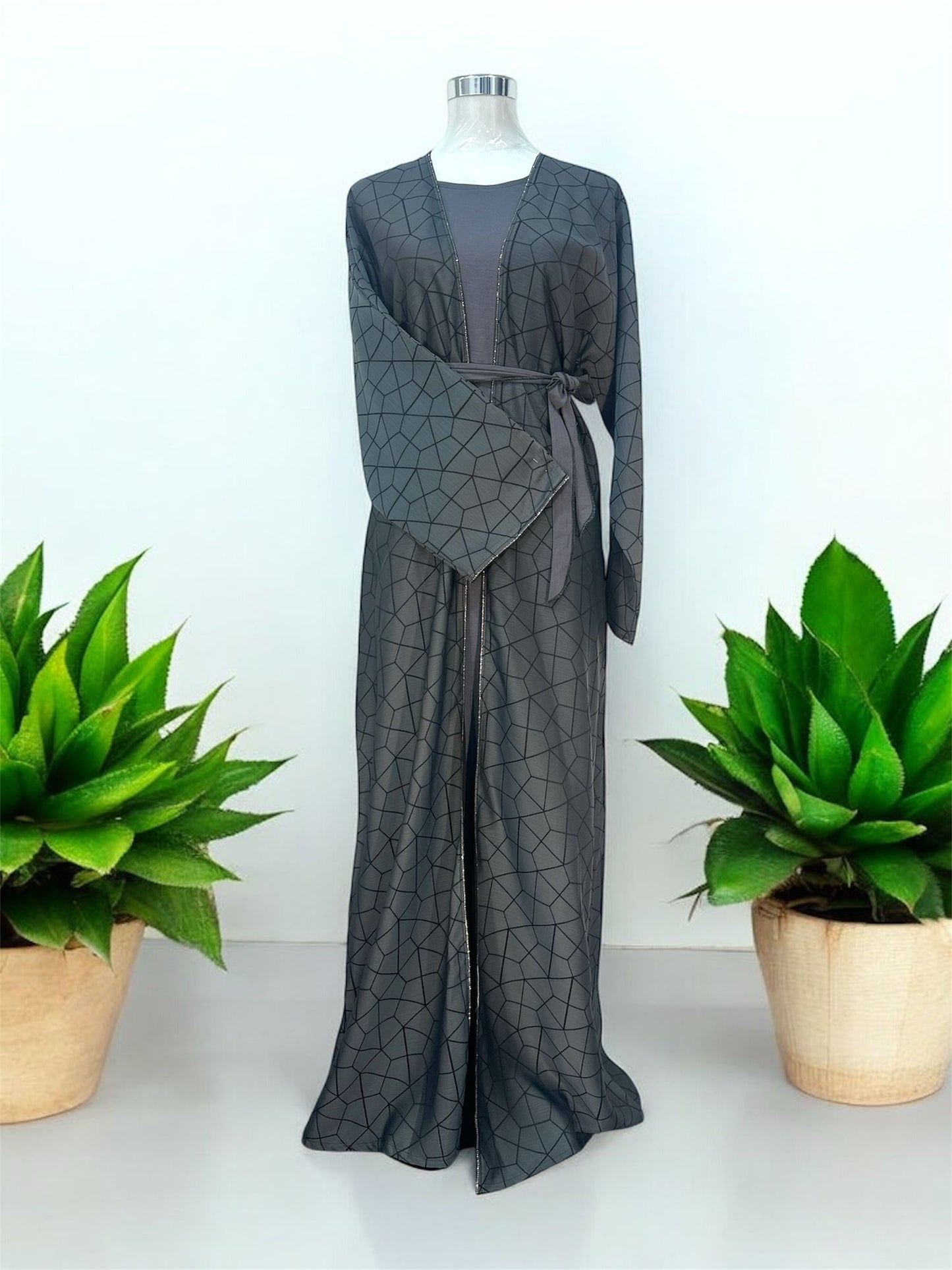 This elegant abaya features a stylish overcoat design, beautifully embellished with stones along the slits and sleeves. The innerwear includes a short-sleeved garment for comfortable layering, complemented by a matching belt that accentuates the waist. A coordinating shawl completes the ensemble, adding a touch of sophistication and grace. Perfect for those seeking a blend of classic charm and modern elegance.