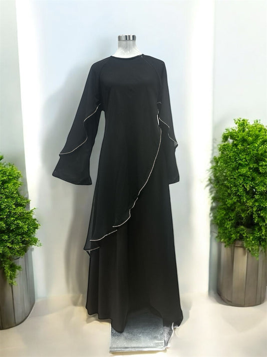 Our Izza black abaya was crafted in timeless black with zip on the left shoulder, this piece is elevated by a beautifully asymmetrical ruffle overlay, creating soft movement and a refined silhouette and it comes with shawl.