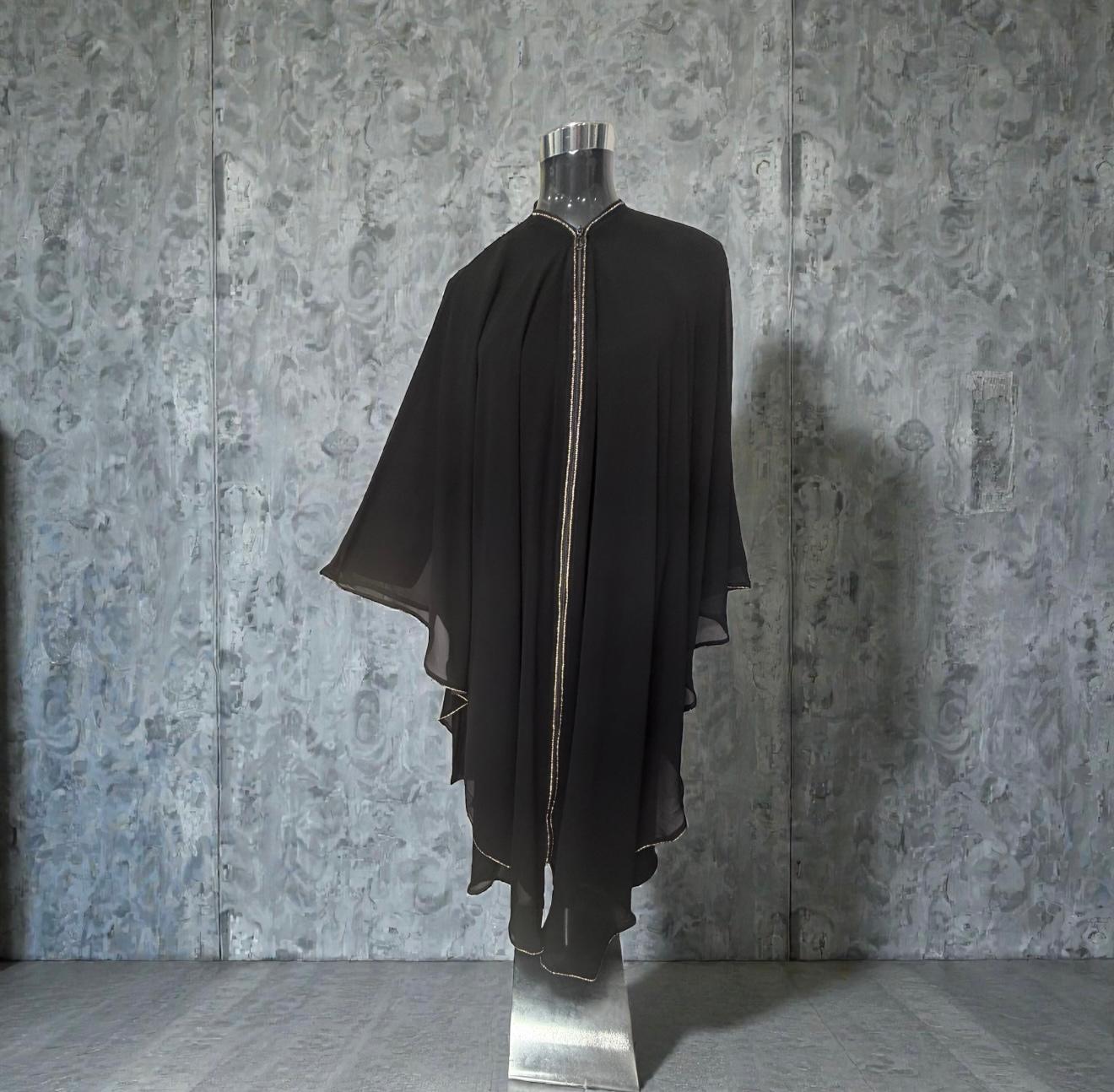 An elegant flowing abaya crafted with a loose, draped silhouette for a graceful and modest look. Designed with wide cape-style sleeves and delicate embellished trim detailing along the front and edges, this piece exudes timeless sophistication. Made from lightweight fabric with a soft, airy flow, it offers both comfort and effortless elegance for special occasions, gatherings, and evening wear. A refined statement piece for a luxurious modest wardrobe.