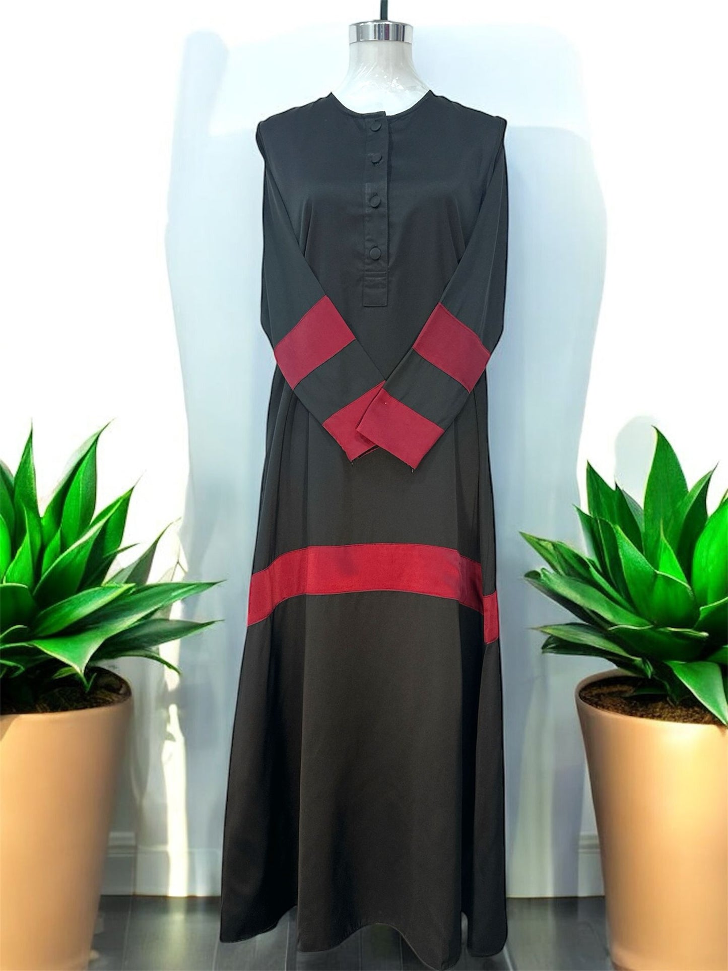 Maroon Liniah jubah is tailored in loose, flowy silhouette that drapes beautifully, offering both comfort and sophistication. A round neckline with a buttoned front placket adds subtle structure, while the wide contrast cuffs and matching hem panel create a striking, coordinated look.