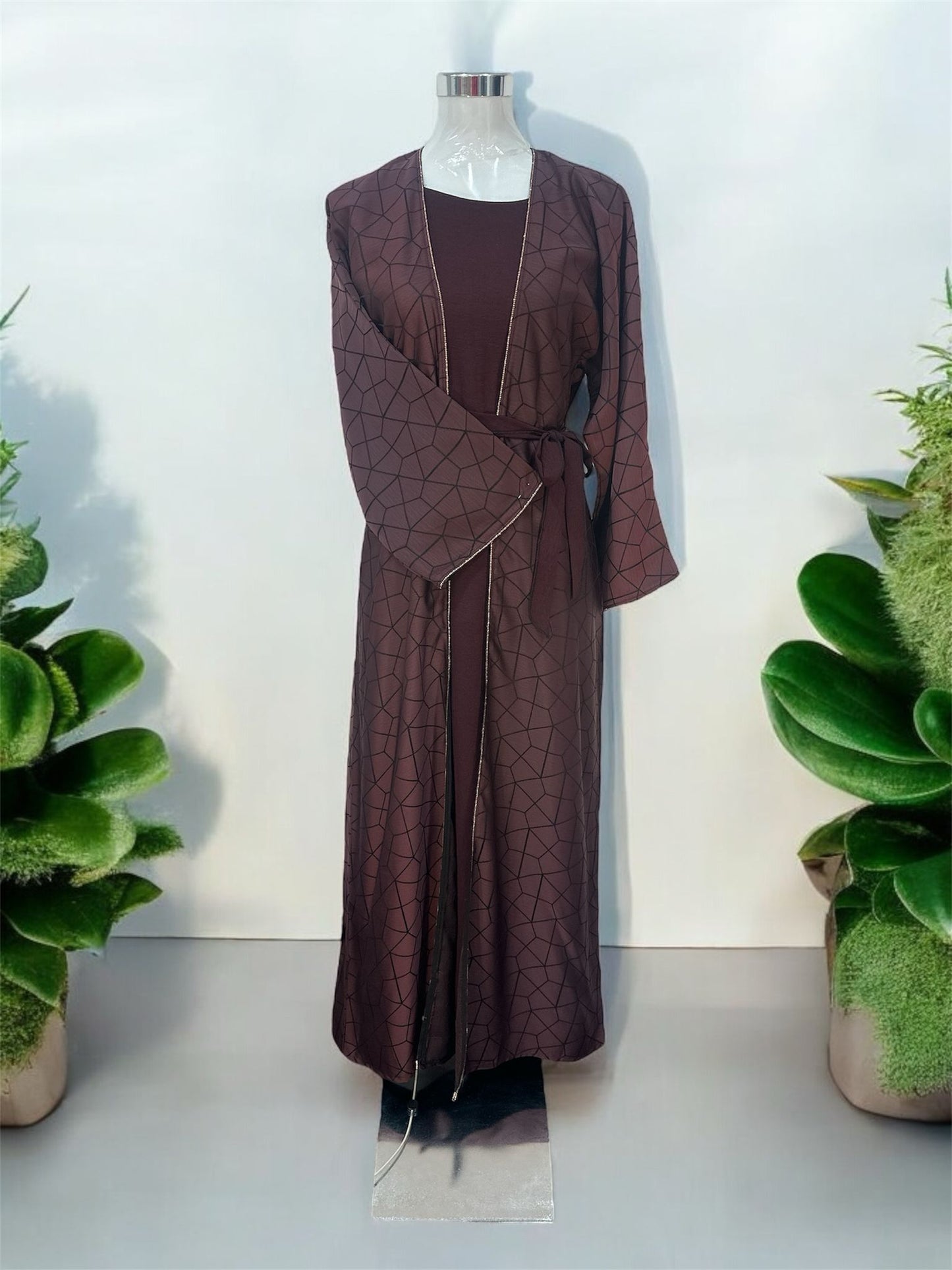This elegant abaya features a stylish overcoat design, beautifully embellished with stones along the slits and sleeves. The innerwear includes a short-sleeved garment for comfortable layering, complemented by a matching belt that accentuates the waist. A coordinating shawl completes the ensemble, adding a touch of sophistication and grace. Perfect for those seeking a blend of classic charm and modern elegance.