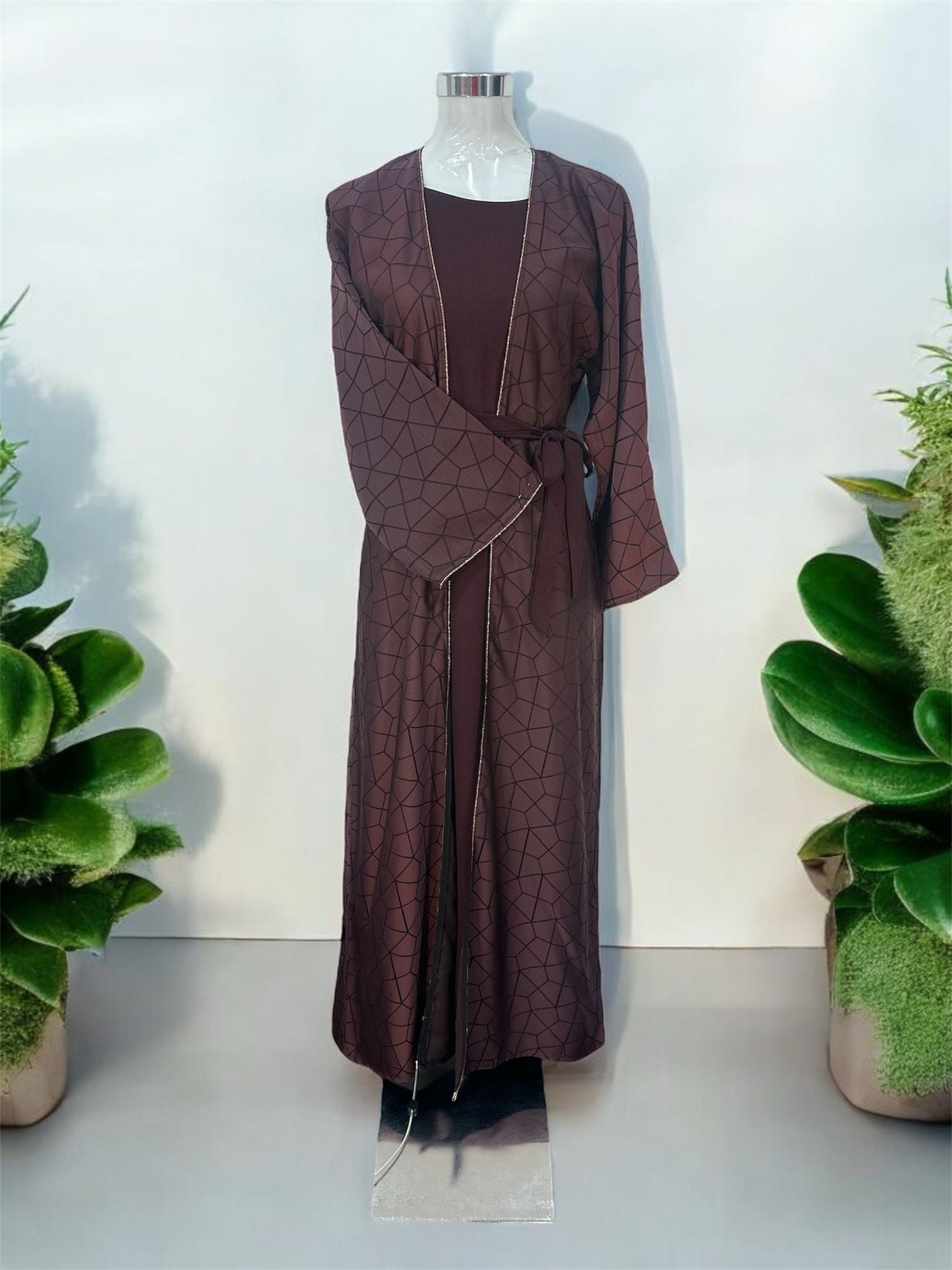 This elegant abaya features a stylish overcoat design, beautifully embellished with stones along the slits and sleeves. The innerwear includes a short-sleeved garment for comfortable layering, complemented by a matching belt that accentuates the waist. A coordinating shawl completes the ensemble, adding a touch of sophistication and grace. Perfect for those seeking a blend of classic charm and modern elegance.