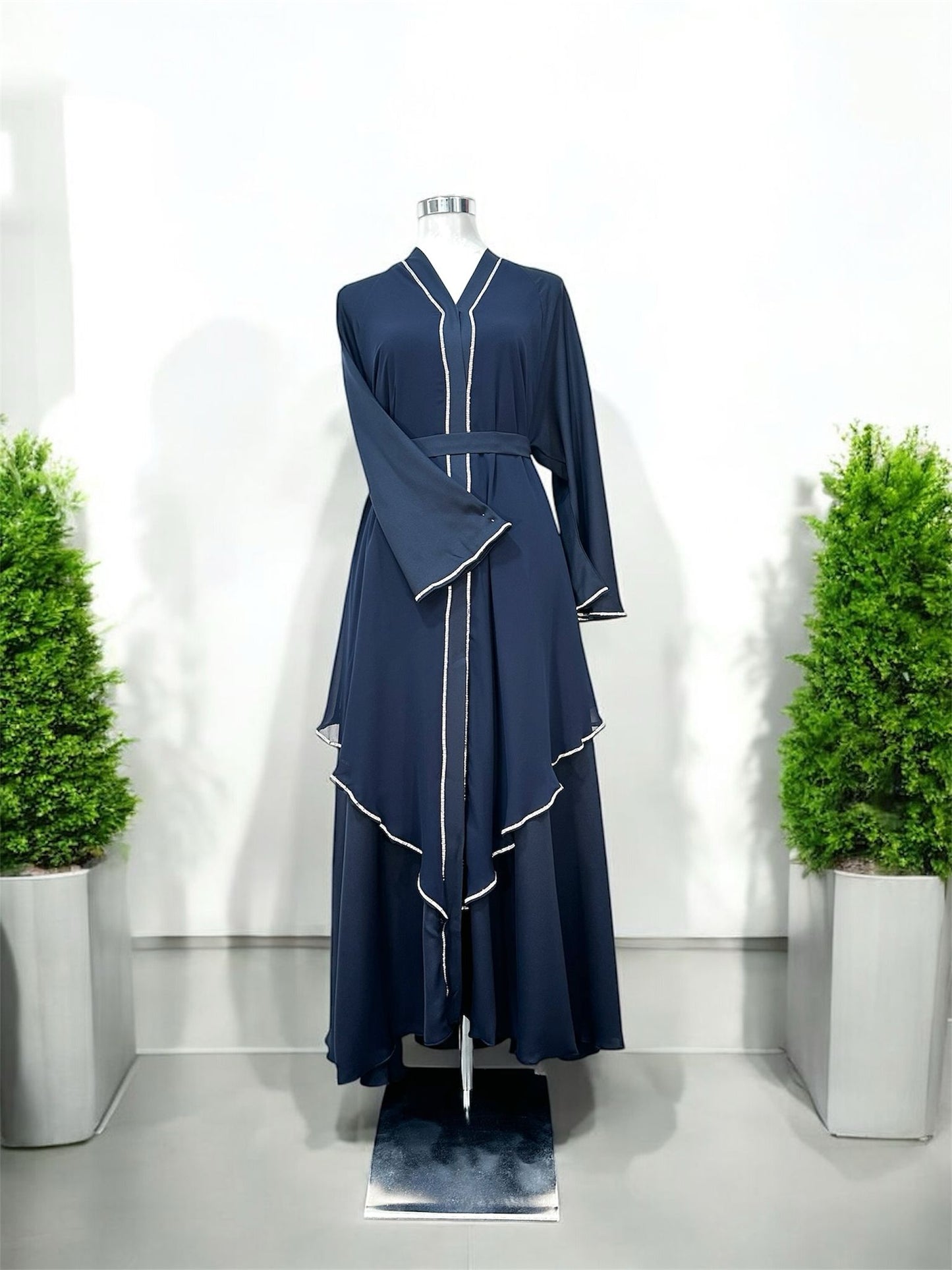 Malika Abaya was designed with flowing layered panels that create beautiful movement and a sophisticated silhouette. The delicate contrast trim detailing along the neckline, front panels, sleeves, and cascading layers adds a refined and modern touch.

Featuring wide flare sleeves and a matching waist belt, this piece offers both comfort and a flattering fit.