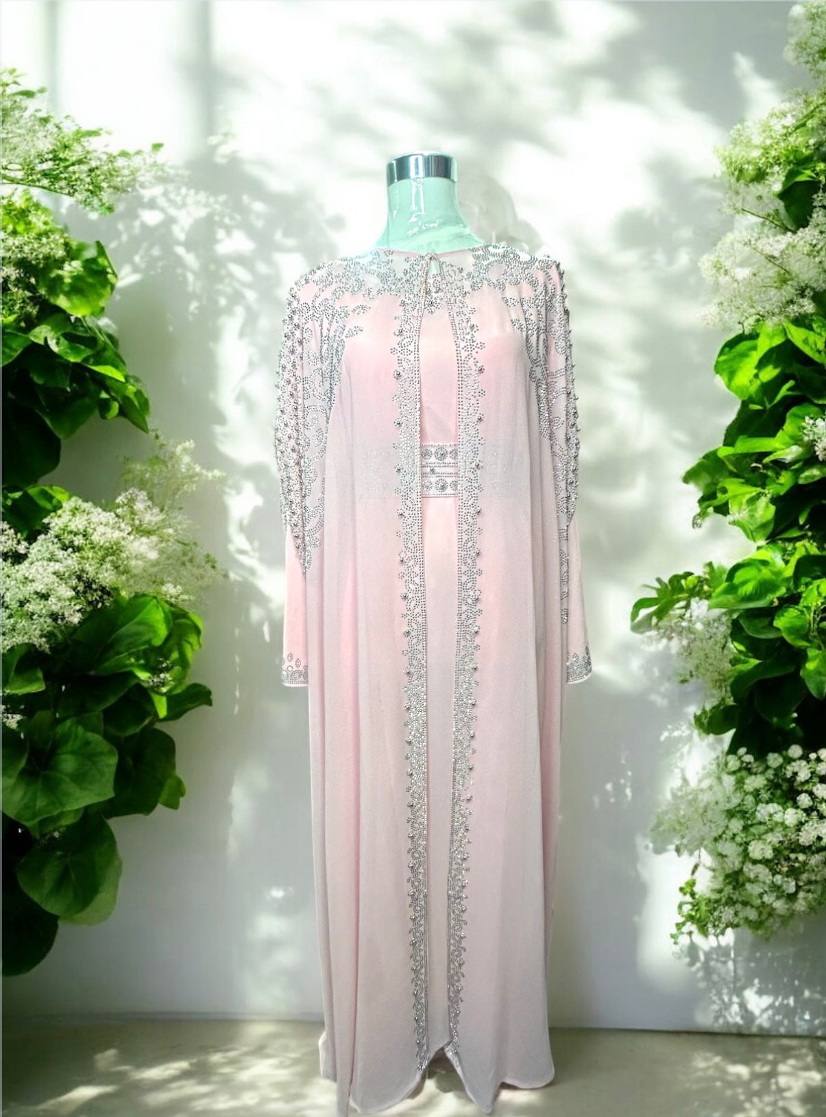 A Pink abaya designed with a flowing cape, delicately adorned with shimmering stone embellishments for a graceful and sophisticated finish.