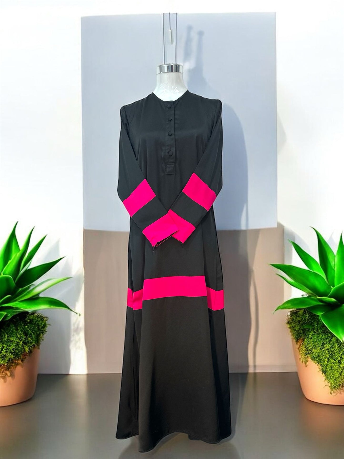 Pink Liniah jubah is tailored in loose, flowy silhouette that drapes beautifully, offering both comfort and sophistication. A round neckline with a buttoned front placket adds subtle structure, while the wide contrast cuffs and matching hem panel create a striking, coordinated look.