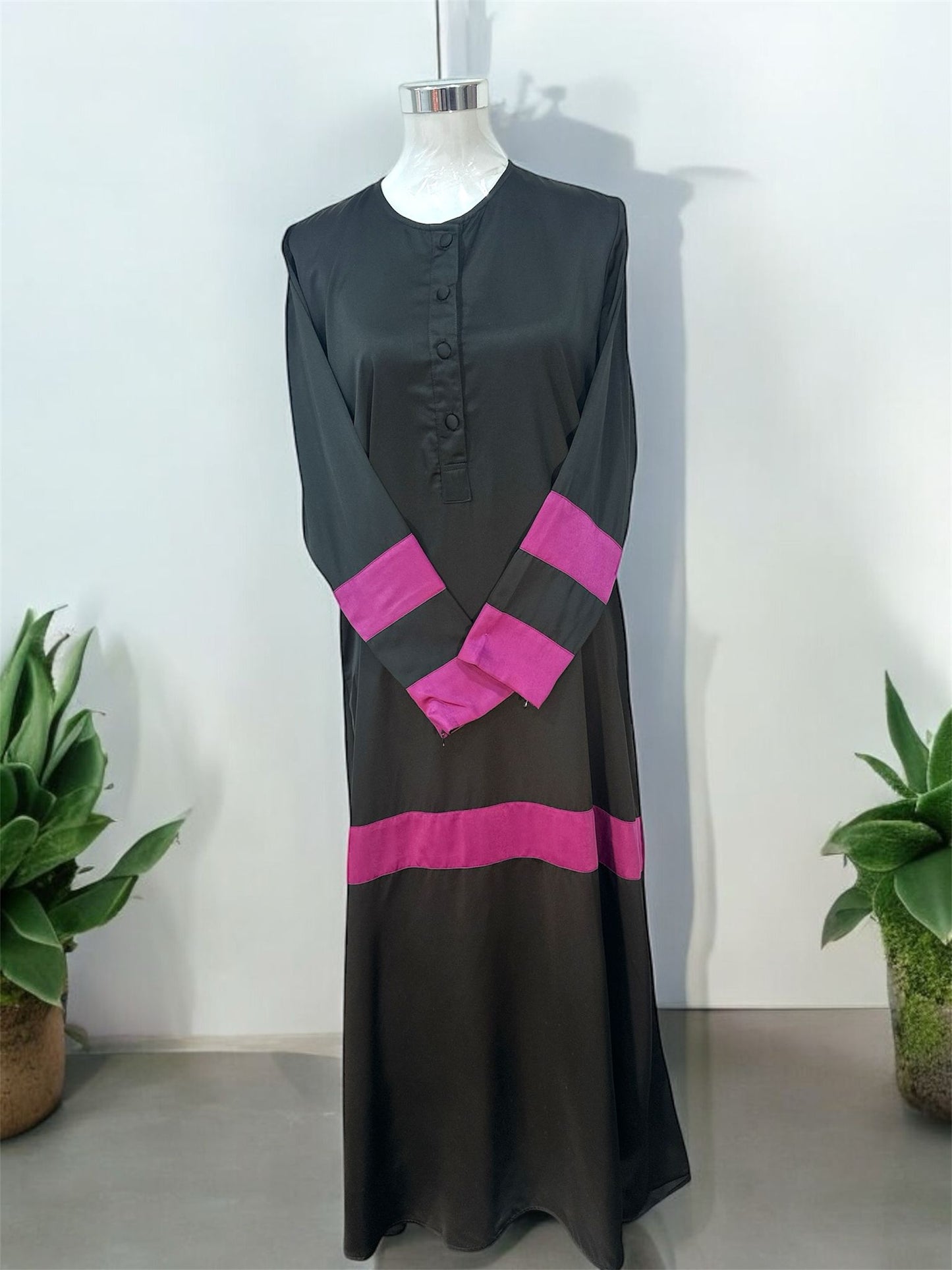 Purple Liniah jubah is tailored in loose, flowy silhouette that drapes beautifully, offering both comfort and sophistication. A round neckline with a buttoned front placket adds subtle structure, while the wide contrast cuffs and matching hem panel create a striking, coordinated look.