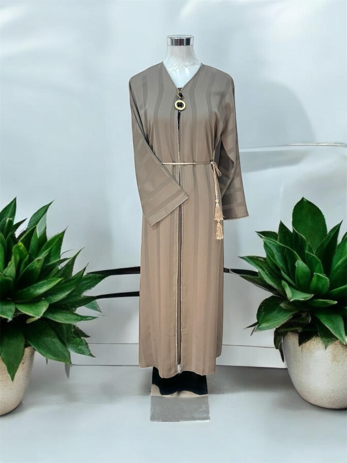 Elevate your modest wardrobe with this elegant Ruqi Abaya, designed with a soft textured finish and a graceful flowing silhouette. Featuring delicate embellished trim detailing along the front and cuffs, this piece offers a refined and timeless look. The look is completed with a braided rope belt with tassel accents and a statement pendant detail at the neckline for an added touch of sophistication.