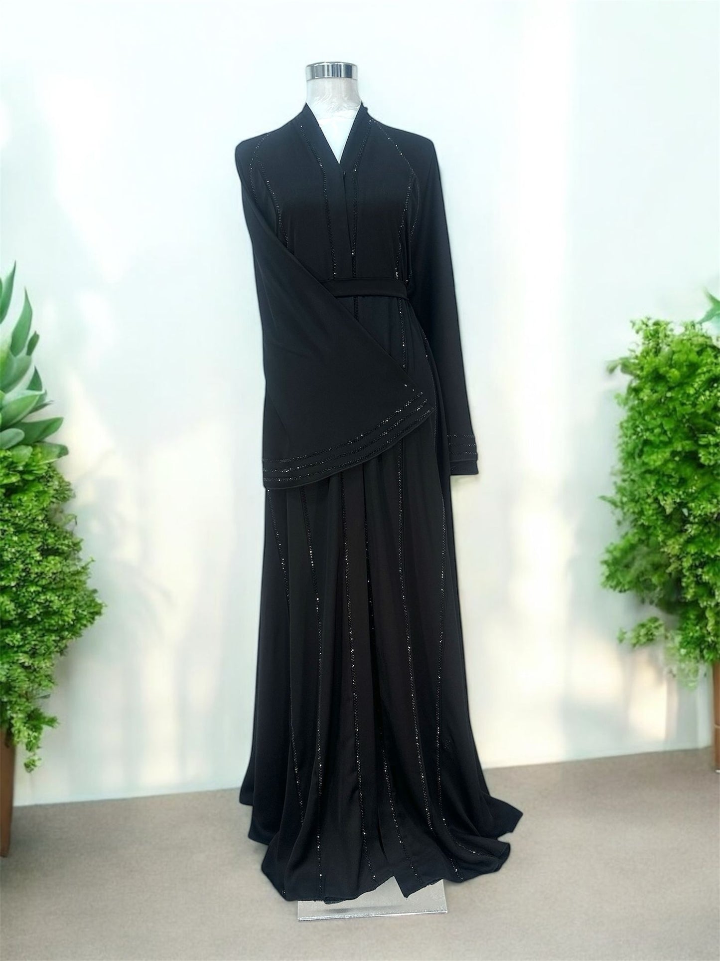 Featuring a structured shawl collar neckline, it brings a polished and sophisticated touch to a beautifully fluid silhouette. Delicate linear embellishments are thoughtfully placed along the front and throughout the skirt, creating a subtle shimmer that enhances movement and elongates the figure.