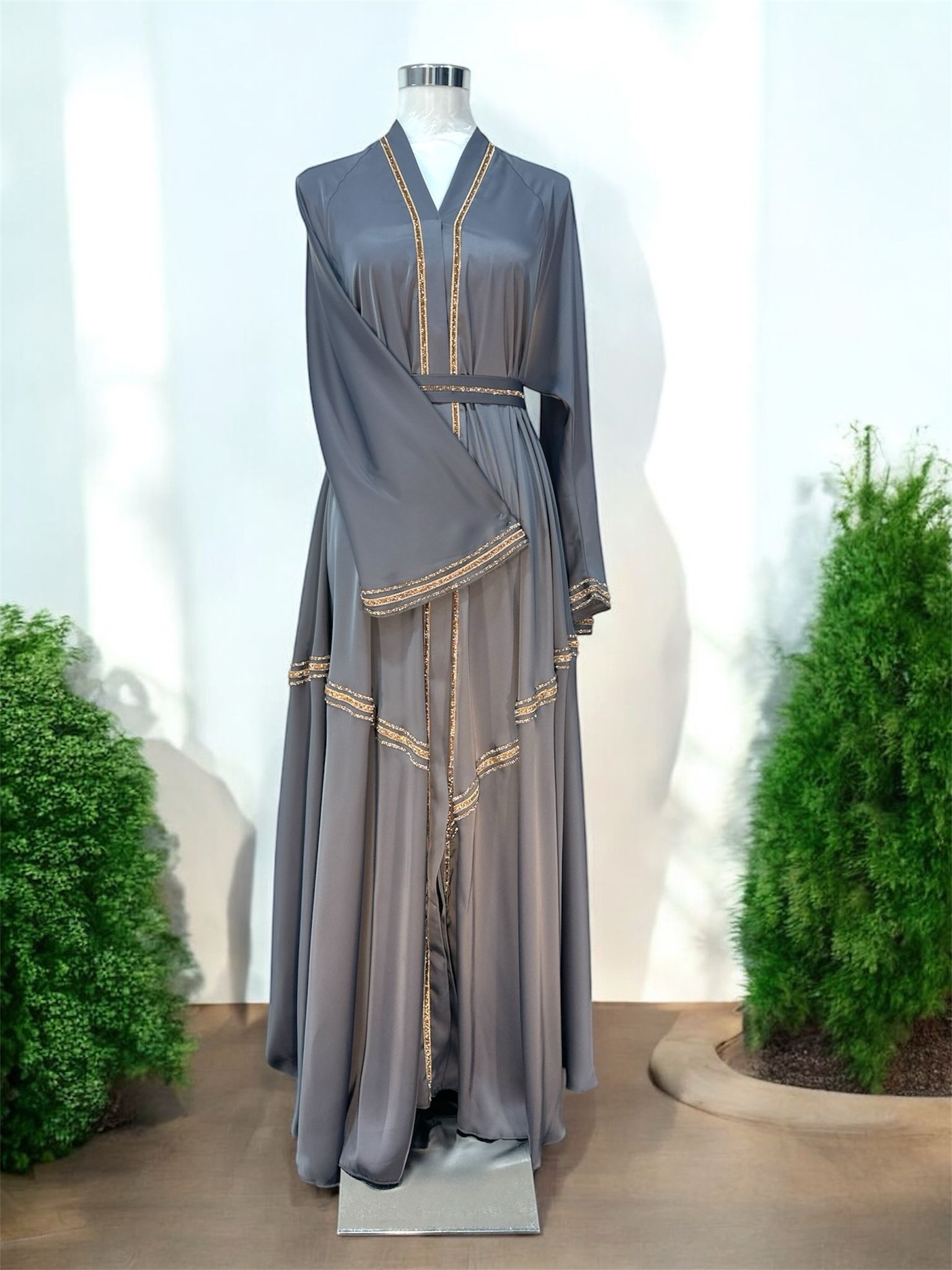 Our Sana abaya silhouette drapes beautifully, while the delicate crystal-trim accents along the neckline, sleeves, waistline, and cascading layers add a touch of understated glamour.

Featuring wide flare sleeves and soft layered panels, this piece creates graceful movement with every step. The matching waist belt enhances the silhouette for a flattering and feminine finish.