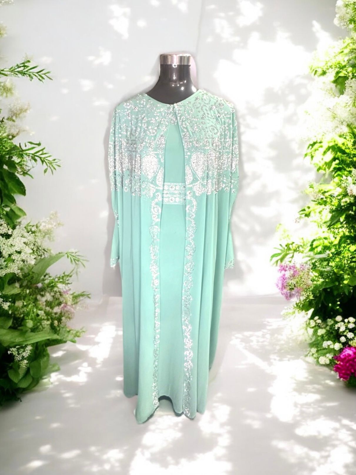 A Turquoise abaya designed with a flowing cape, delicately adorned with shimmering stone embellishments for a graceful and sophisticated finish.


