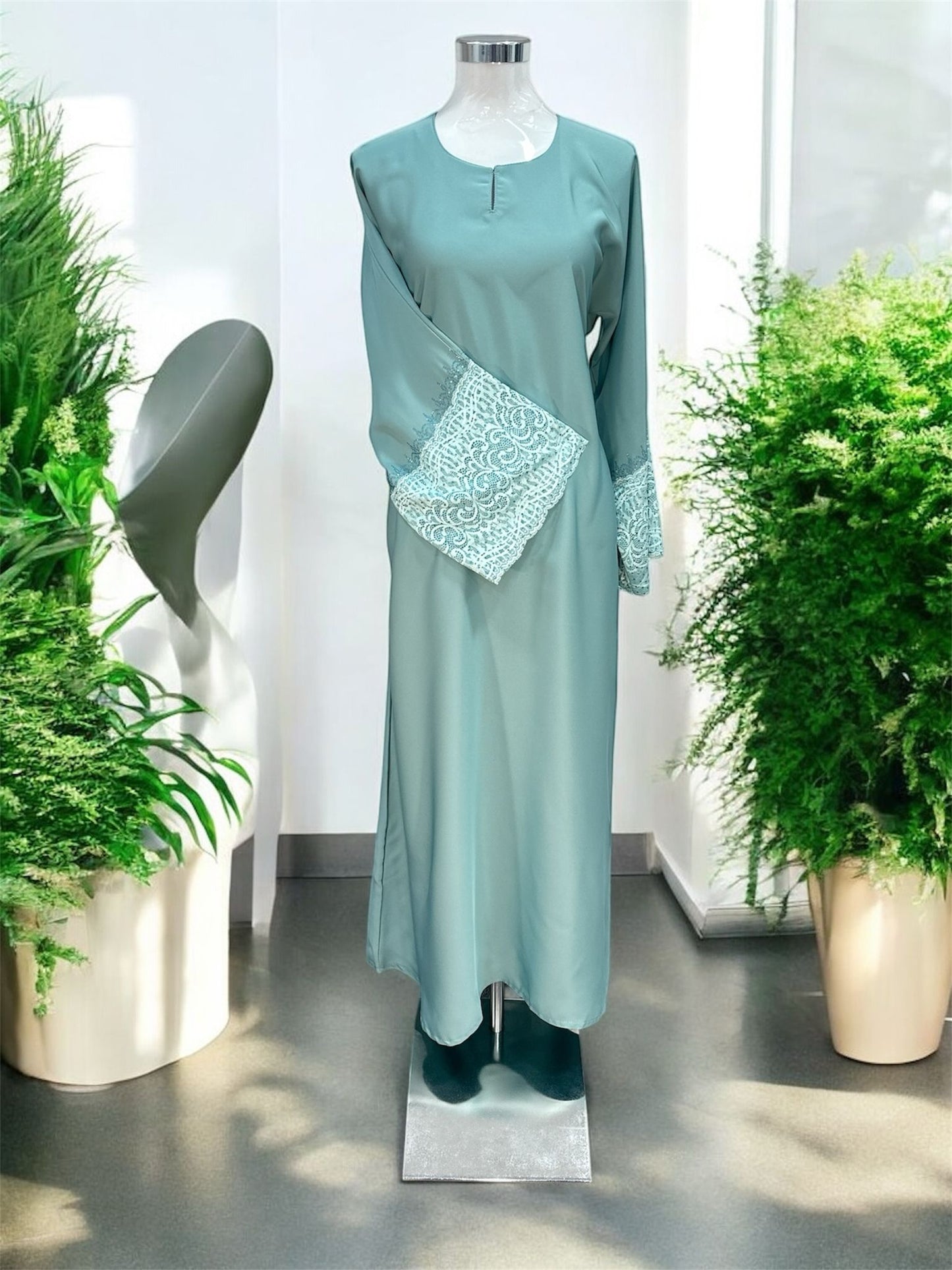 Turquoise Nisa jubah falls in a clean, elongated line, creating a flattering drape that moves beautifully with every step. A subtle V-notched round neckline adds a modern touch, while the standout feature lies in the delicately crafted lace cuffs—intricately detailed to elevate the overall design with a hint of femininity and refinement and it is paired with a shawl.
