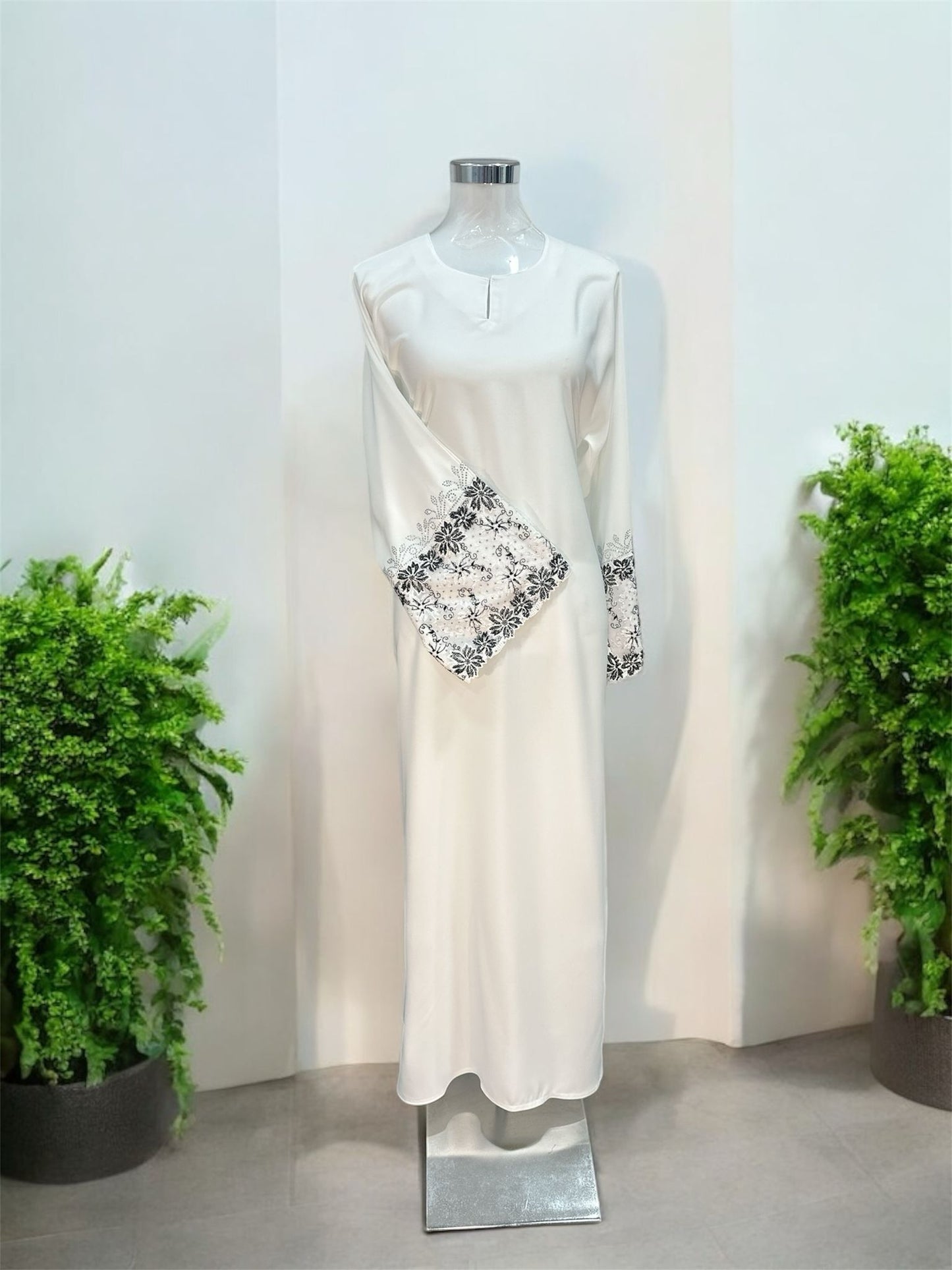 White Nisa jubah falls in a clean, elongated line, creating a flattering drape that moves beautifully with every step. A subtle V-notched round neckline adds a modern touch, while the standout feature lies in the delicately crafted lace cuffs—intricately detailed to elevate the overall design with a hint of femininity and refinement and it is paired with a shawl.