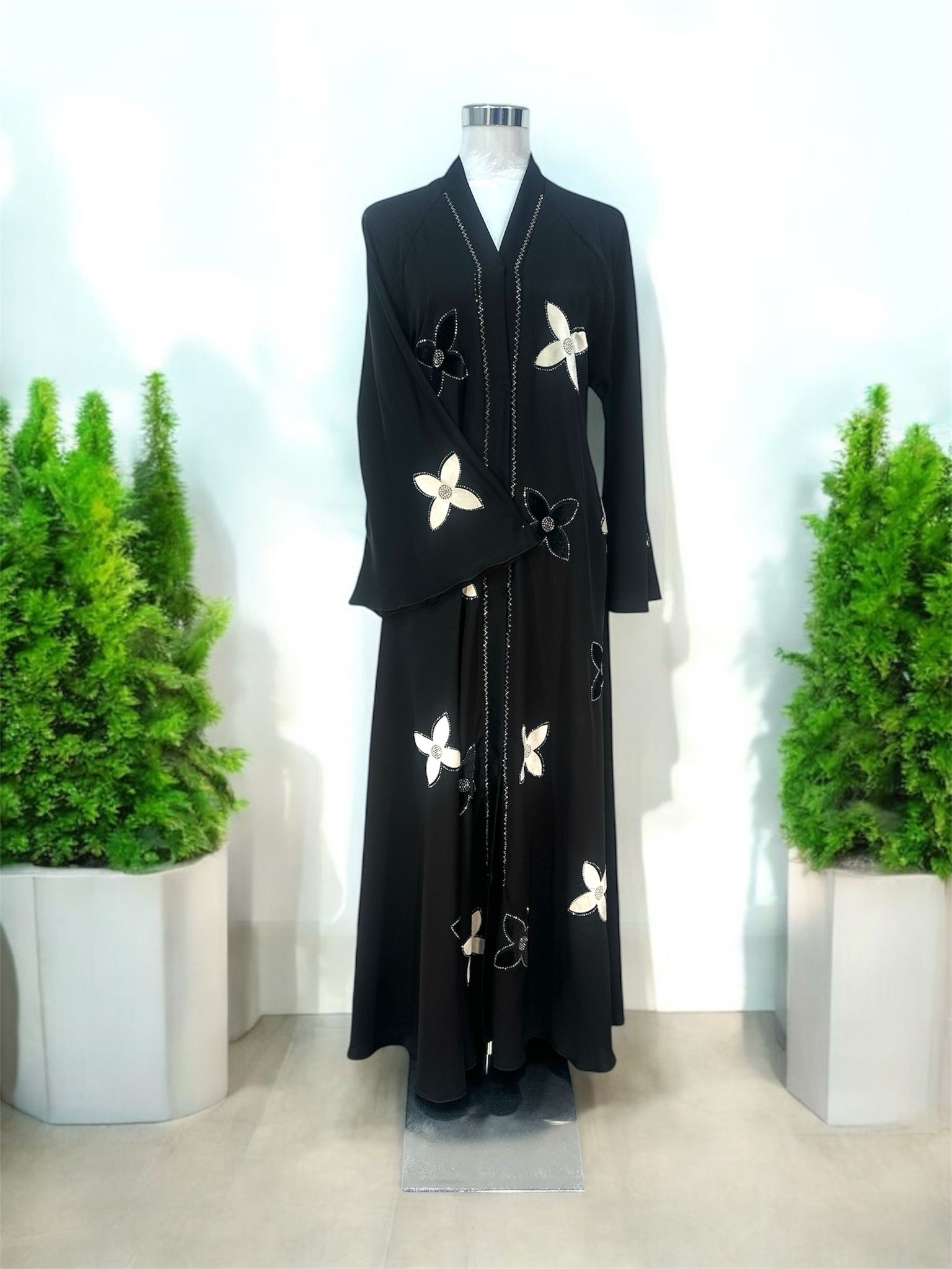 Our Yasmin Abaya is enhanced with delicate snap-button blossom accents across the overcoat and sleeves, adding texture and a unique decorative touch and elevated with subtle stone embellishments along the slit, offering a hint of understated sparkle, while the coordinating shawl completes the ensemble with effortless elegance.