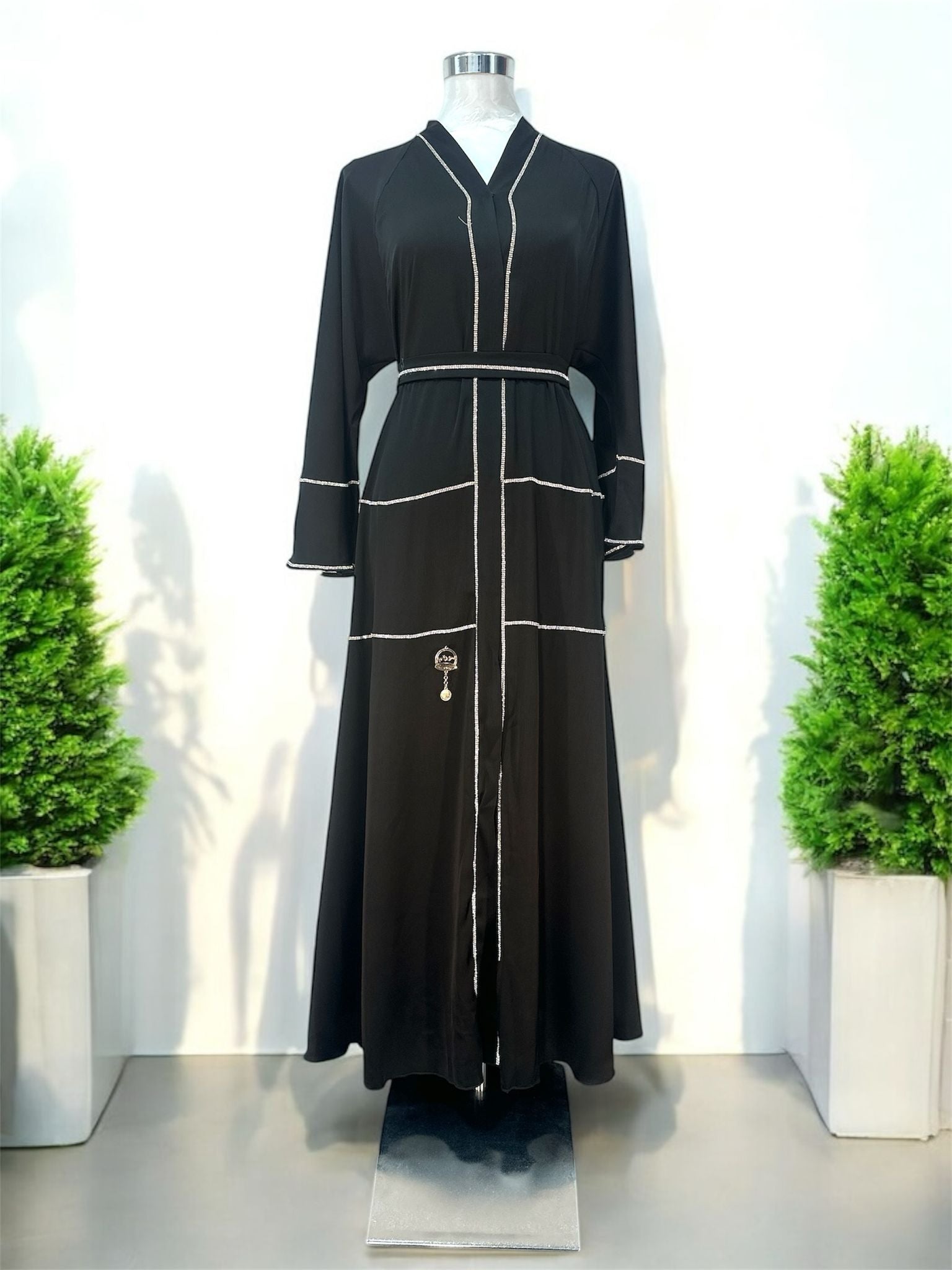 Our Zayn Abaya features a flattering V-neckline with snap button. The panel-style layout enhances the flow of the garment, while a small decorative charm detail adds a unique finishing touch.